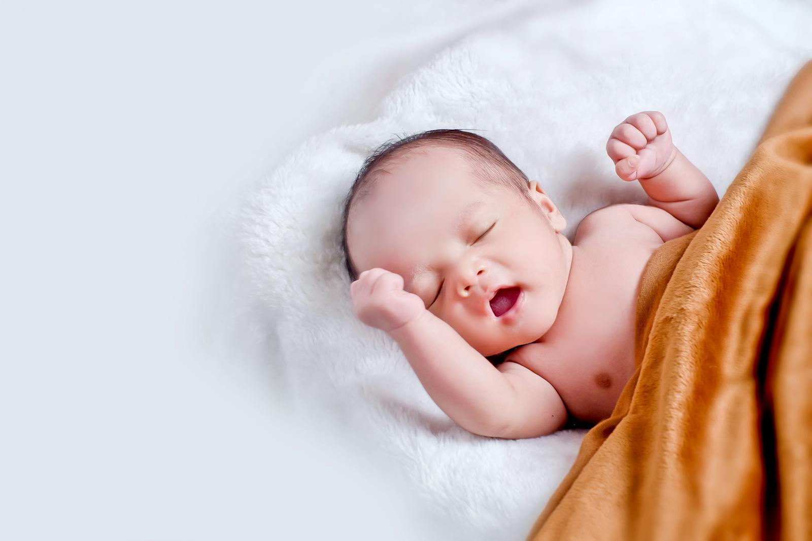 A peaceful sleeping infant wrapped in a soft, warm blanket on a cozy white surface.