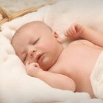 A peaceful sleeping baby nestled in a soft, fluffy blanket inside a wicker basket.