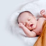 A peaceful sleeping infant wrapped in a soft, warm blanket on a cozy white surface.