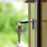 Key inserted in door lock against a blurred green background, symbolizing security and real estate.