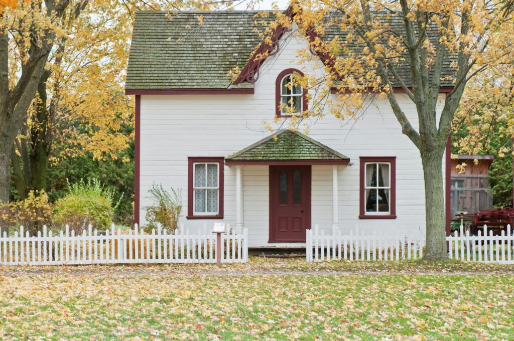 Picturesque traditional house with autumn foliage and a white picket fence in London, Ontario.