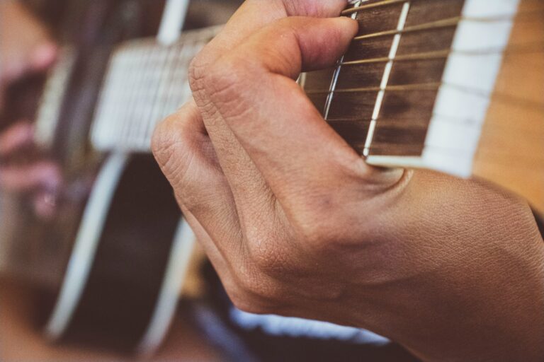 person playing guitar in grayscale photography