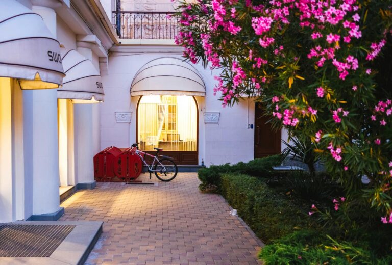 Serene evening view of a boutique hotel entrance in Sochi, adorned with vibrant flowers and warm lighting.