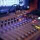 Close-up of a professional audio mixing console with glowing LED indicators.