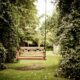 A tranquil wooden swing hanging in a verdant garden setting, ideal for relaxation.