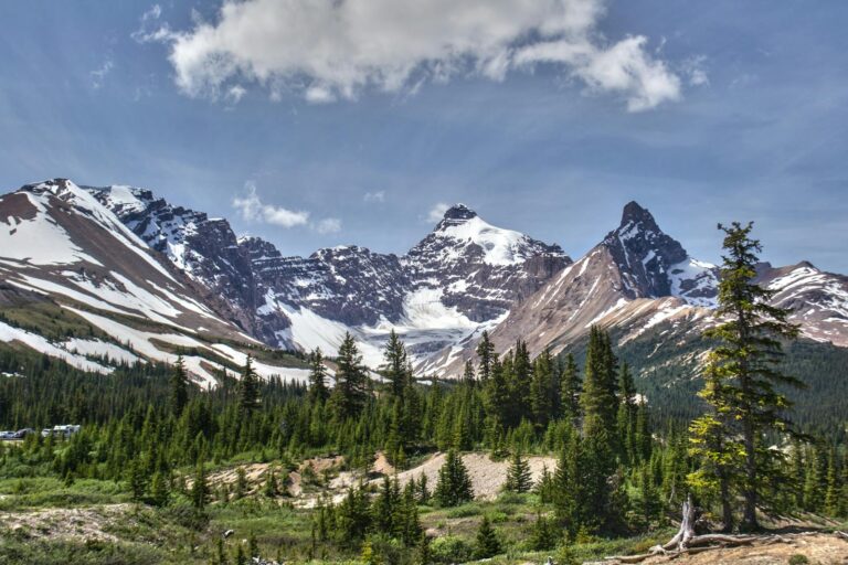 Capture of the majestic snow-capped Rocky Mountains in Banff under a sunny sky.