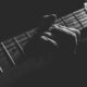 grayscale photo of person holding guitar neck and strings