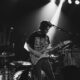 greyscale photo of man playing electric guitar on stage