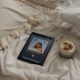 a tablet sitting on a bed next to a cup of coffee